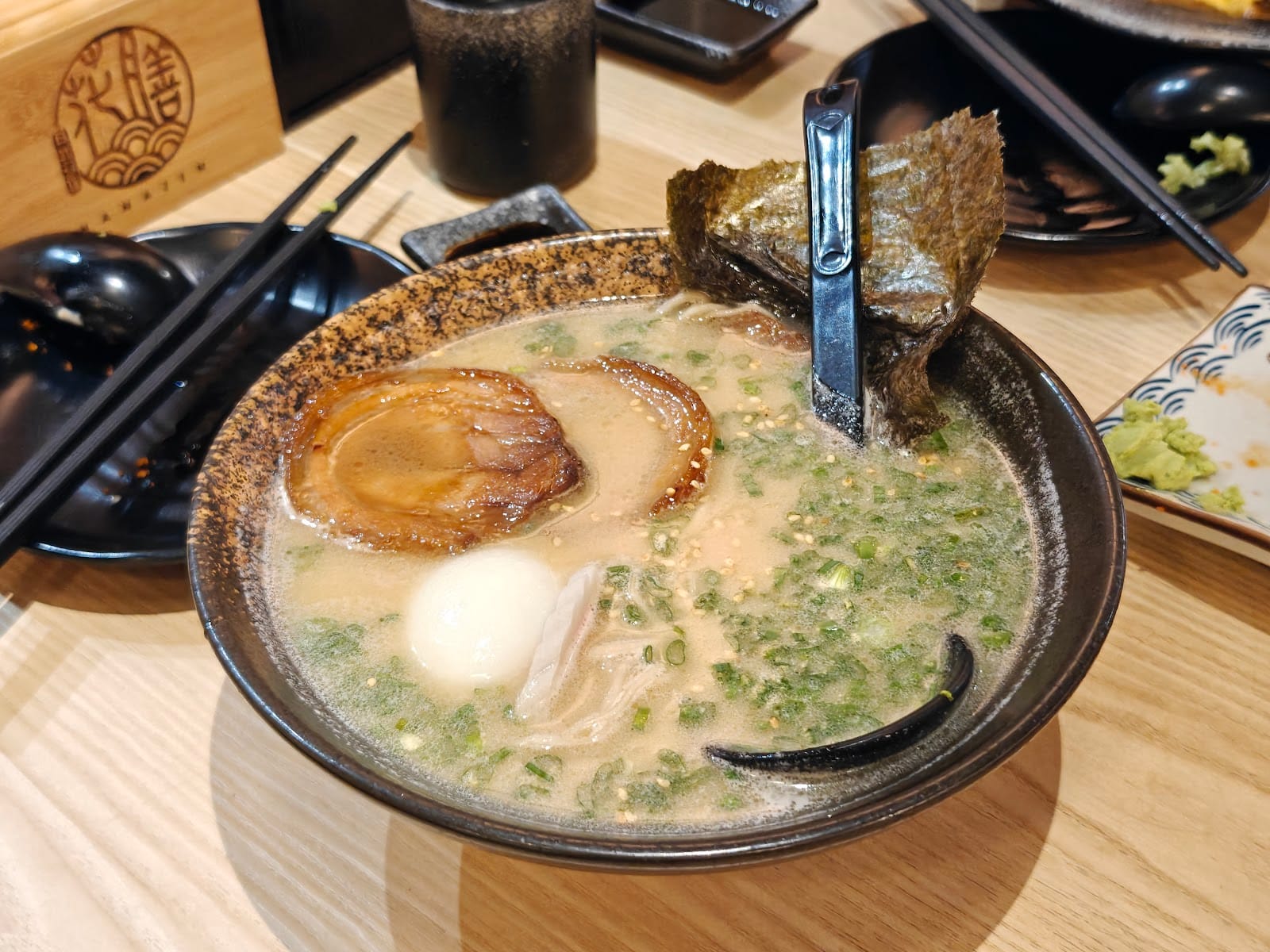 A bowl of ramen with chashu, a soft-boiled egg, nori and spring onion