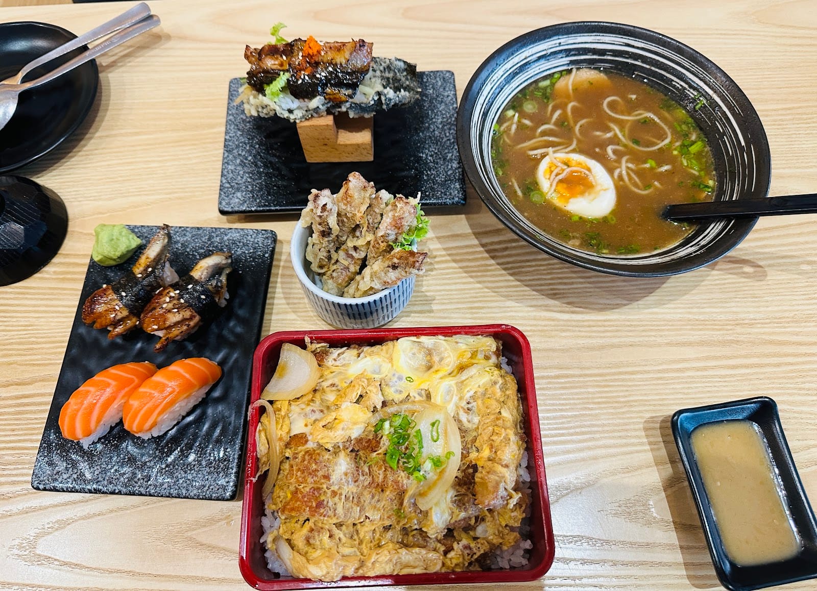 A table of eel and salmon nigiri, hand rolls, tempura, ramen and a katsu rice bowl